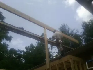 Carpenter setting a ridge beam over a new addition frame — Ice Dam Removal by Roofing Brothers in Sugar Hill