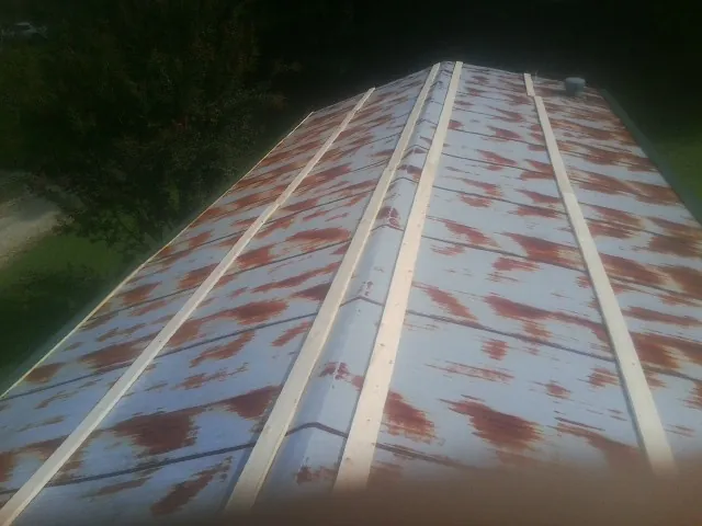 Rusted metal roof panels with new wood purlins before replacement — Storm Damage Roof Repair in Sugar Hill by Roofing Brothers