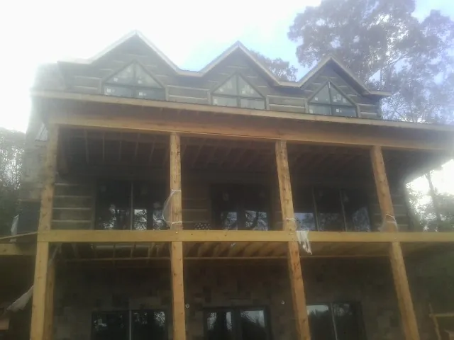 Dormers and porch framing on a large log home under construction — Roof Coating work by our crew in Sugar Hill