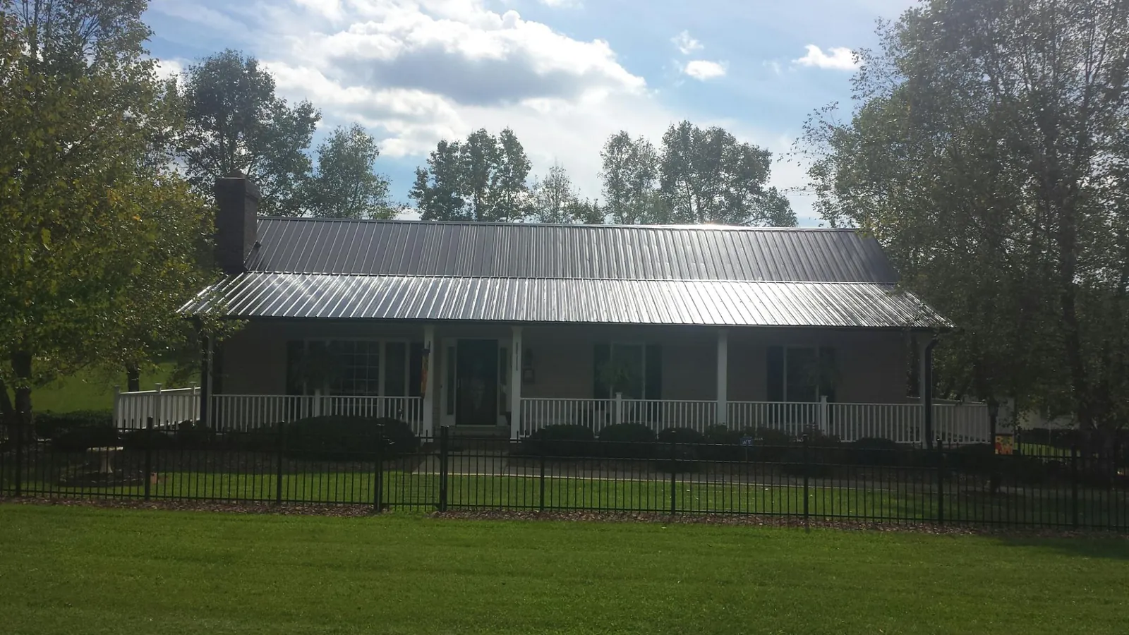 Gray metal roof on a brick ranch with a full width front porch — Gutter Guard Installation work by our crew in Sugar Hill
