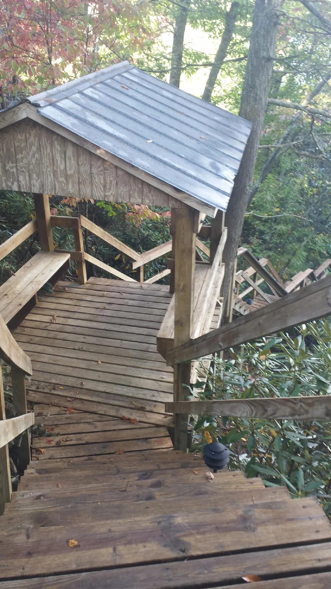 Metal roofed shelter over wooden steps on a wooded walkway — Skylight Repair & Installation work by our crew in Sugar Hill