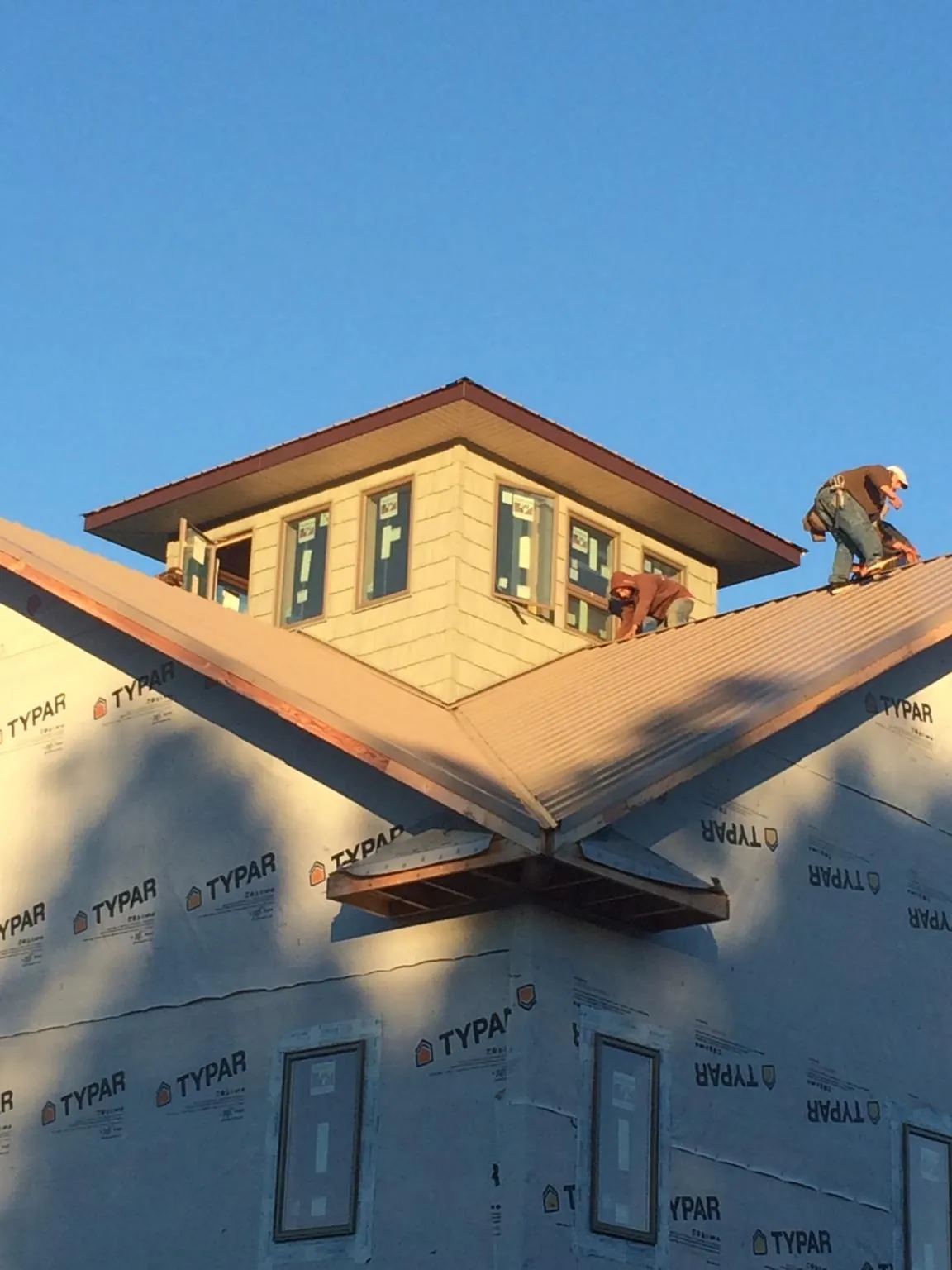 Roofers working around a rooftop cupola on a new metal roof at sunset — Roof Waterproofing in Sugar Hill by Roofing Brothers